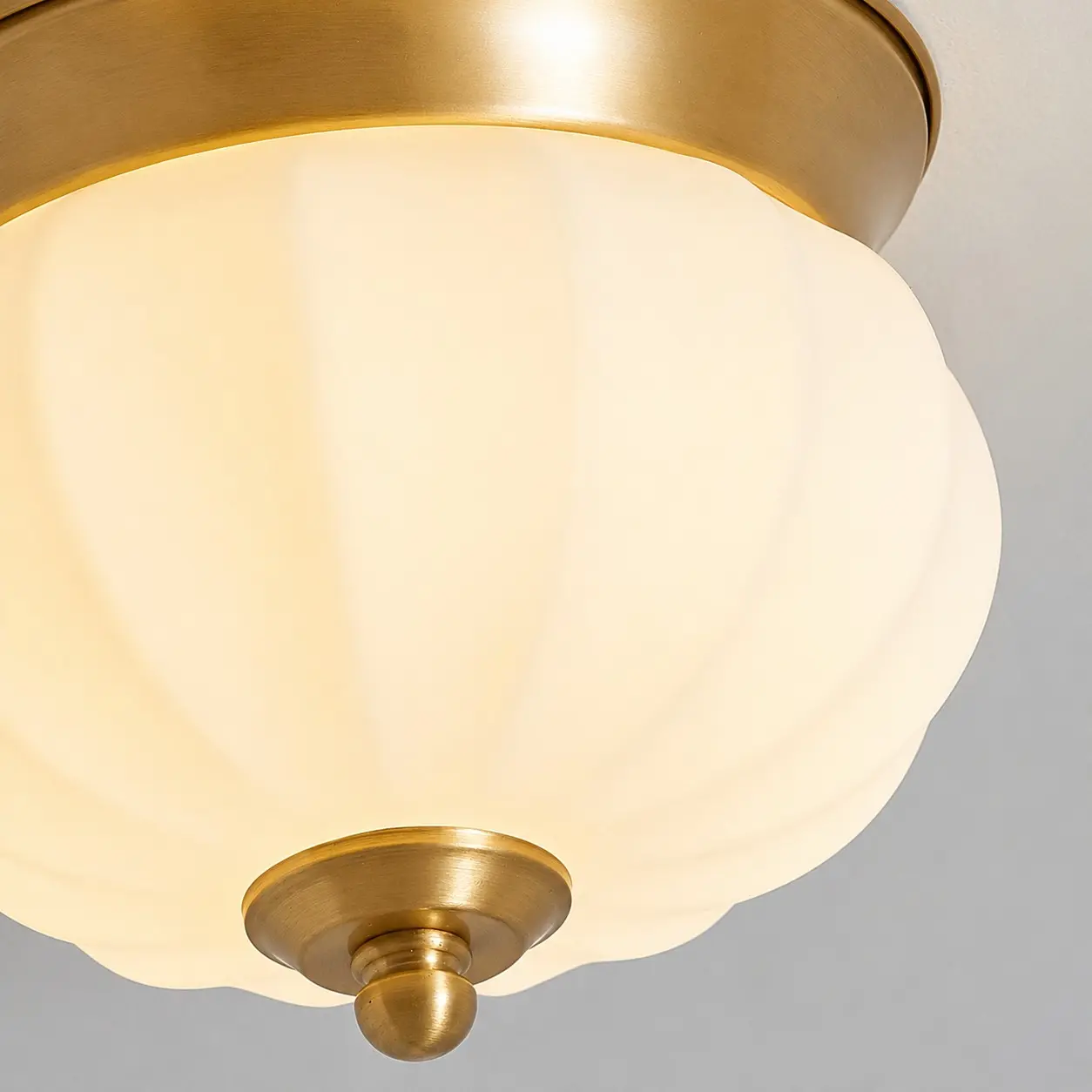 Illuminated opal glass shade and brass finial detail